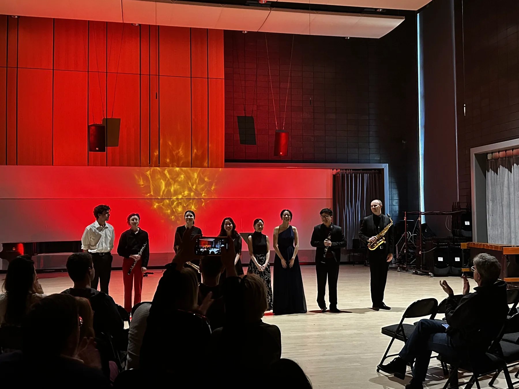 East Zodiac ensemble taking a bow on a red-lit concert stage